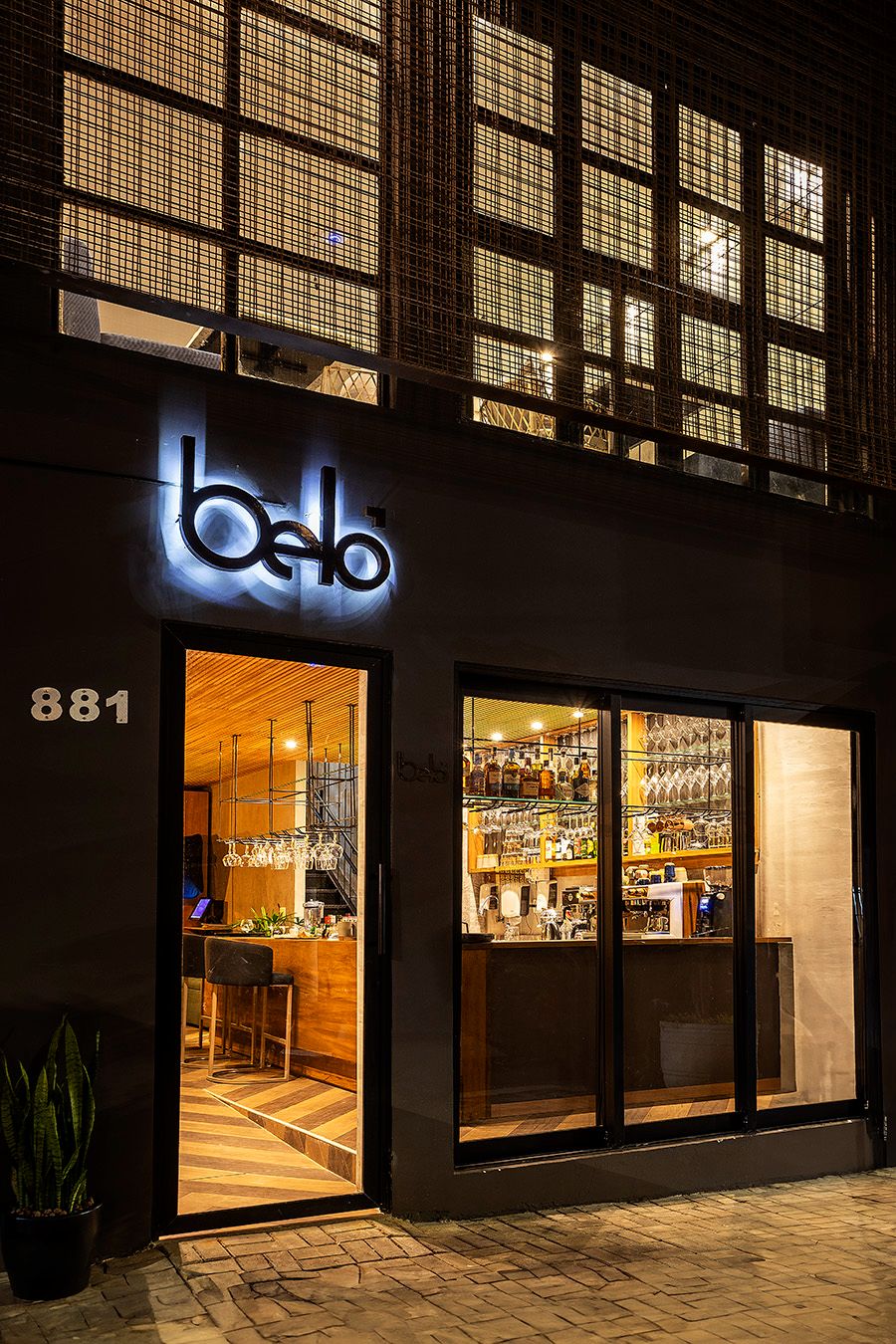 Fachada noturna do Belô Café São Paulo, com letreiro iluminado e calçada de pedra.